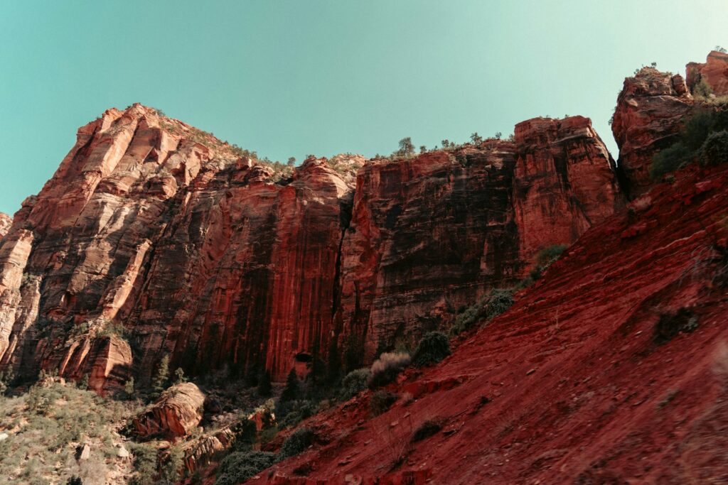 A tall cliff-front of the Red Canyon in Utah, beneath a plain blue sky.