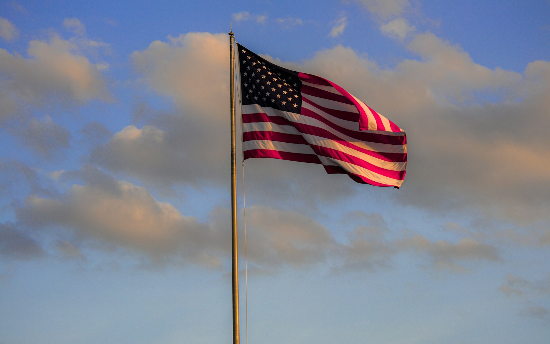 An American flag waves against a sunset sky