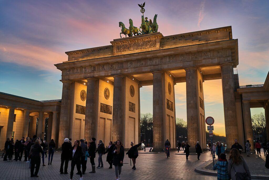 Brandenburg Gate, Germany, at dusk. Lamplight lights the pillars.