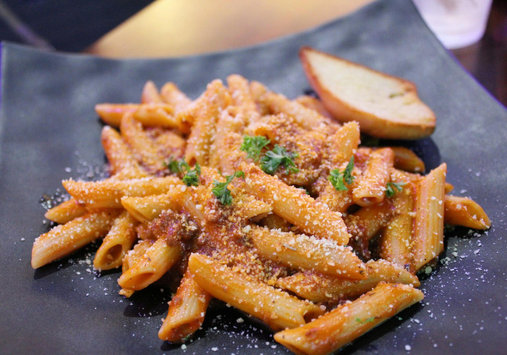 Penne pasta dish on black plate