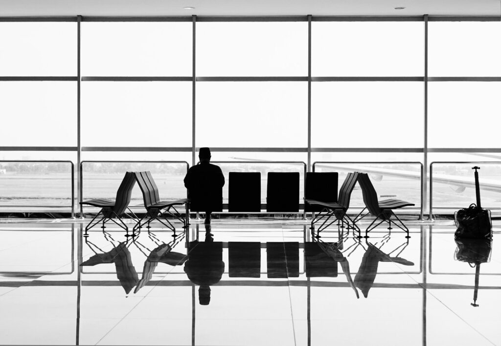 A man sitting in a grayscale airport lounge.