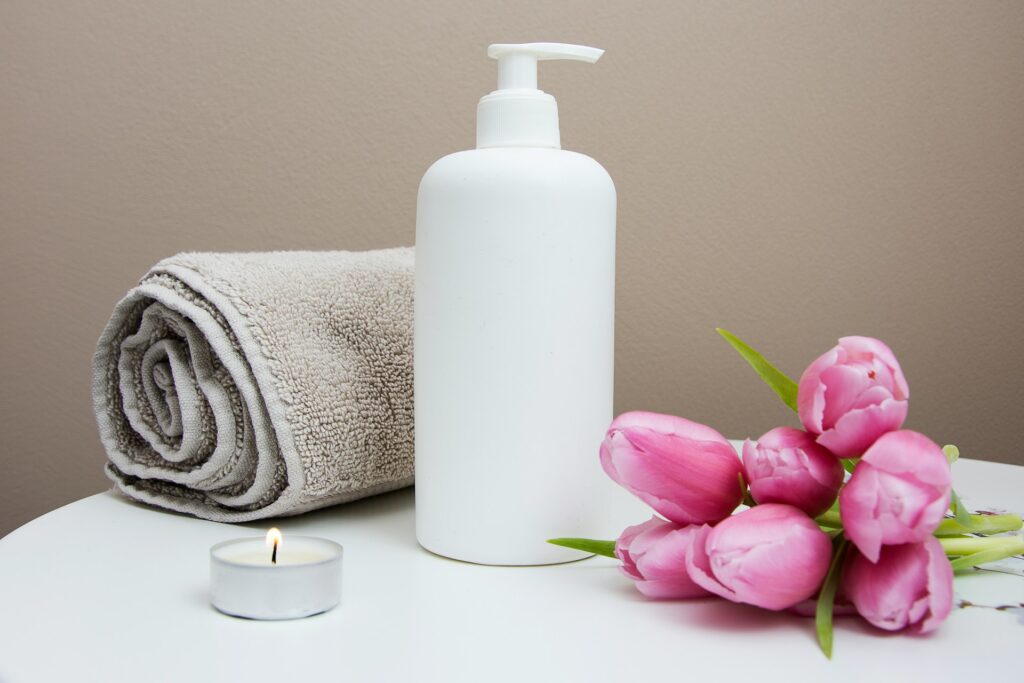 A spa towel, oil and flowers on a marble countertop