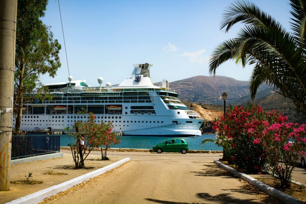 The prow of a passing cruise ship, with palm trees at either side.