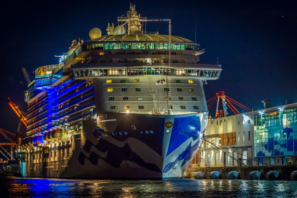 A well-lit cruise ship docked at port at night